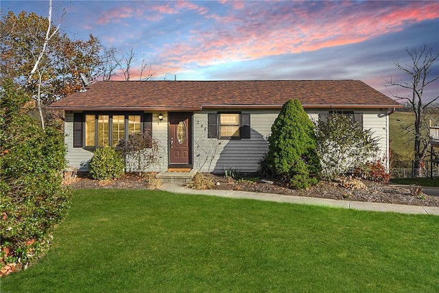 ranch-style home with a front yard and roof with shingles