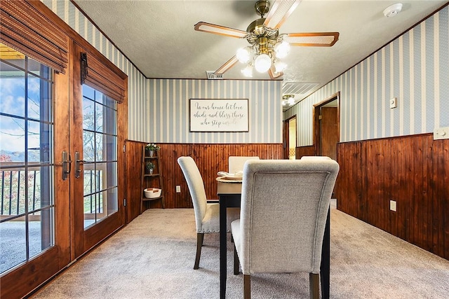 dining space with a wainscoted wall, wallpapered walls, and carpet floors