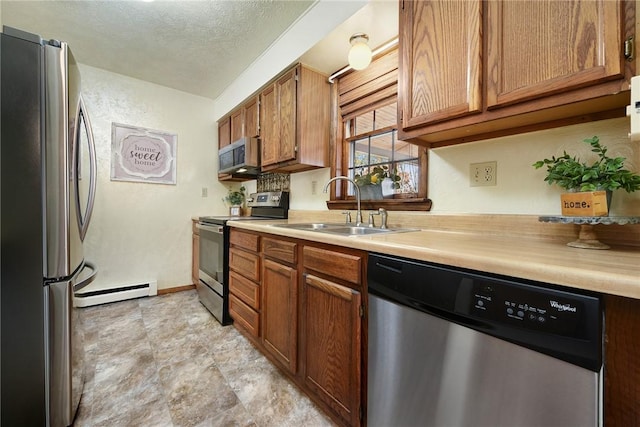 kitchen with a sink, light countertops, appliances with stainless steel finishes, a textured ceiling, and a baseboard radiator