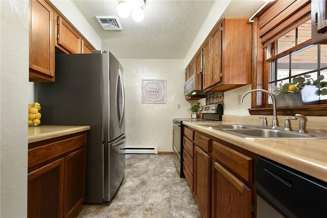 kitchen featuring visible vents, a sink, a textured ceiling, stainless steel appliances, and a baseboard radiator