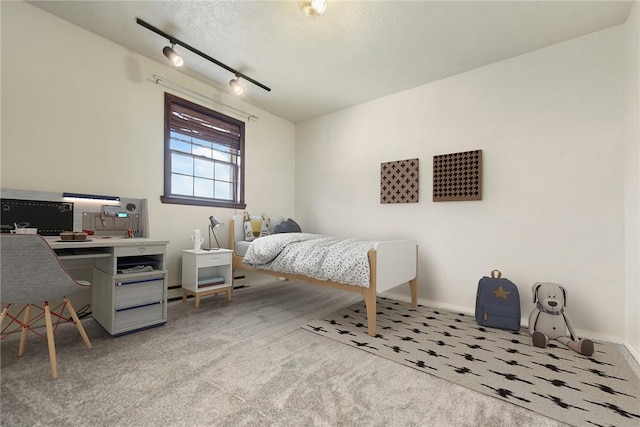 carpeted bedroom featuring track lighting and baseboards