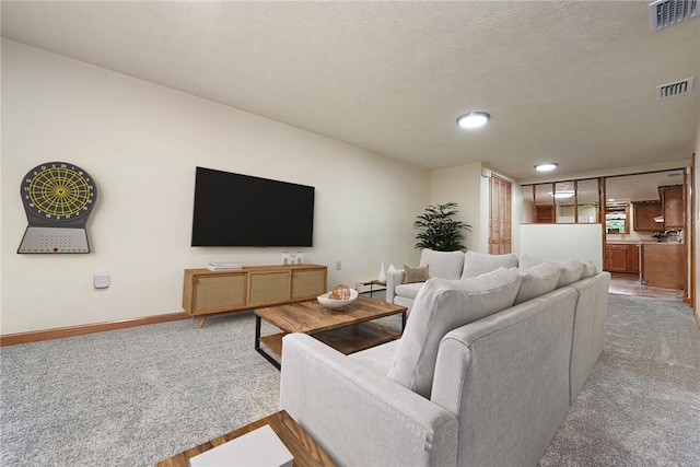 carpeted living room with visible vents, baseboards, and a textured ceiling