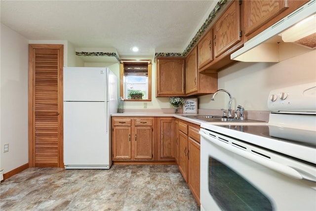 kitchen with brown cabinets, under cabinet range hood, a sink, white appliances, and light countertops