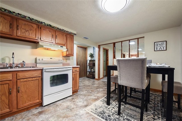 kitchen with under cabinet range hood, brown cabinets, a sink, and white range with electric stovetop