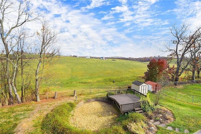 view of yard with a storage unit, an outbuilding, a rural view, and fence