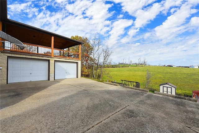 garage with a rural view and concrete driveway