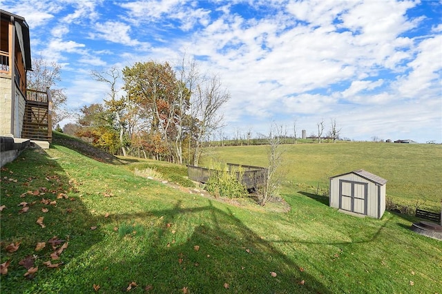 view of yard featuring a rural view, a storage unit, stairs, and an outdoor structure