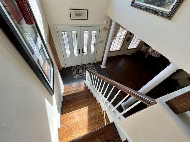 foyer entrance with stairway, a high ceiling, and wood finished floors