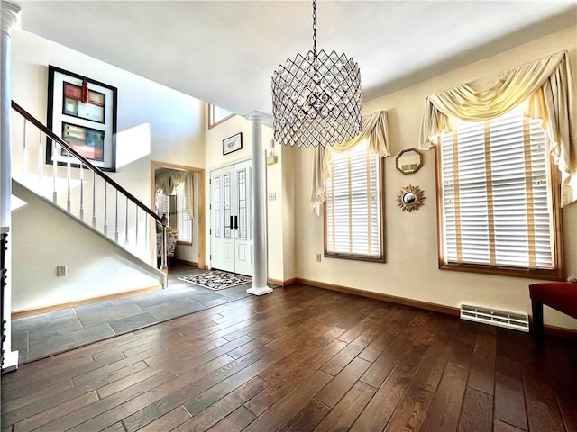 foyer entrance featuring stairway, baseboards, visible vents, dark wood finished floors, and decorative columns