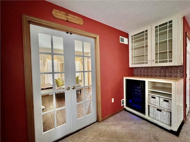 doorway with carpet flooring, french doors, visible vents, and baseboards