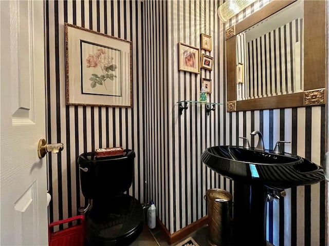 half bathroom with wallpapered walls and toilet