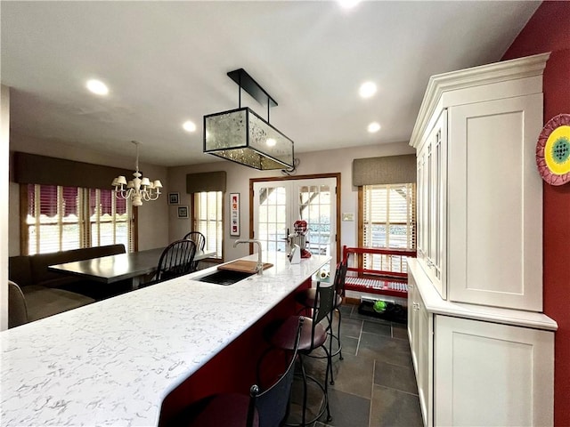 kitchen with a sink, a breakfast bar, recessed lighting, and an inviting chandelier