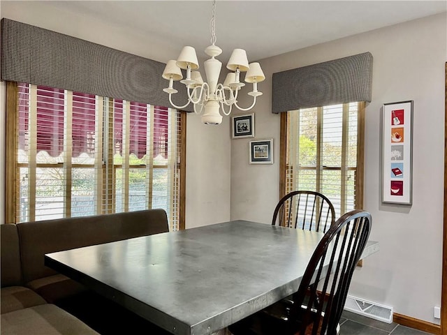 dining space with a chandelier, visible vents, and baseboards