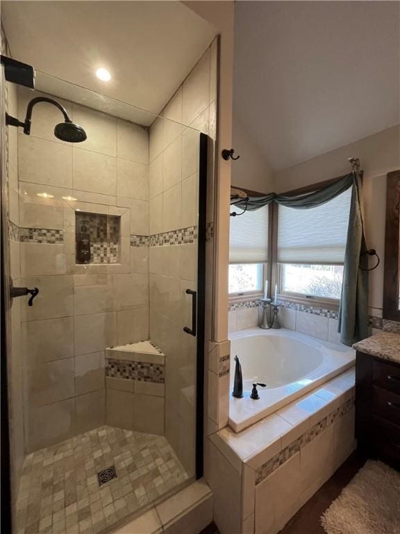 bathroom with a bath, a shower stall, vanity, and vaulted ceiling