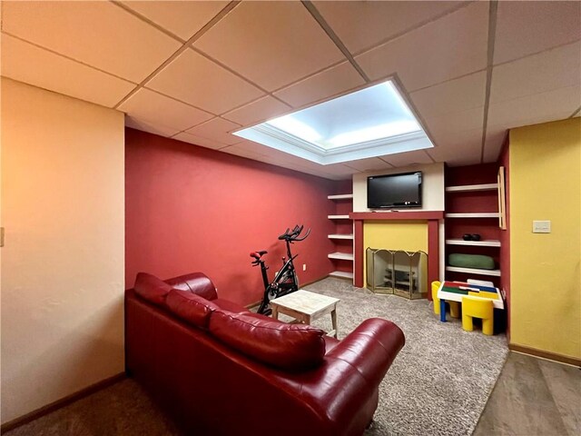 living room featuring a drop ceiling and baseboards