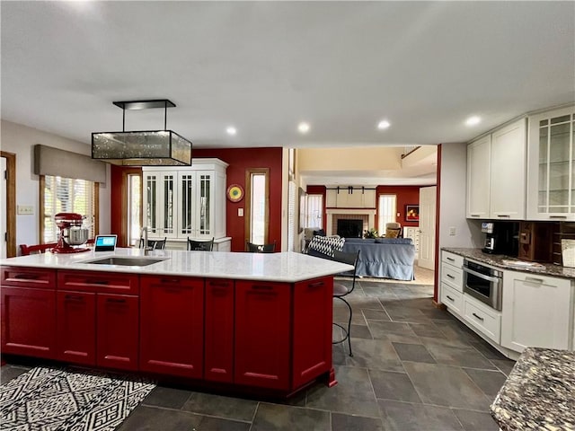 kitchen featuring a kitchen island with sink, open floor plan, recessed lighting, and a sink