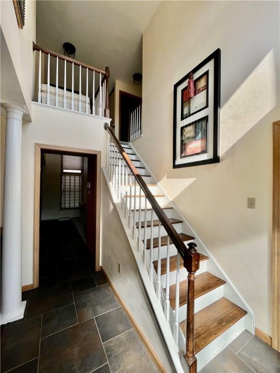 stairway featuring decorative columns and baseboards