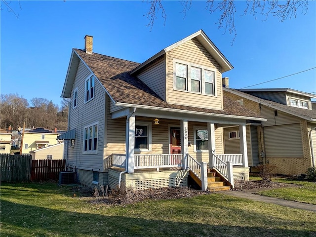 view of front of house with a porch, fence, roof with shingles, a front yard, and a chimney