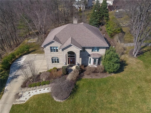 view of front of home with driveway, a chimney, and a front lawn