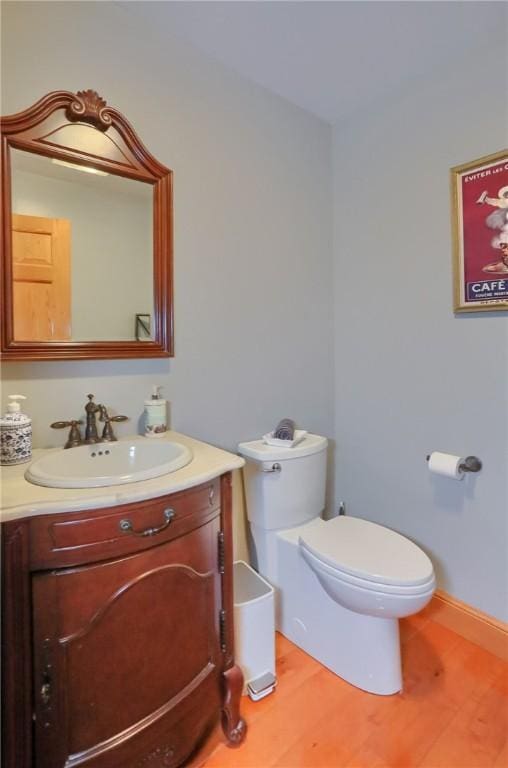 bathroom featuring toilet, vanity, baseboards, and wood finished floors