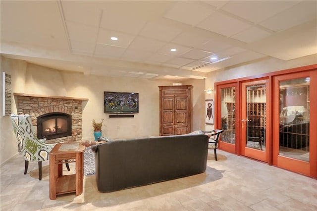 living area with a stone fireplace, recessed lighting, french doors, and a paneled ceiling