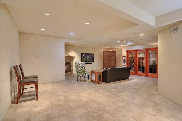 living room featuring visible vents, baseboards, recessed lighting, french doors, and a warm lit fireplace