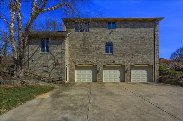 exterior space featuring an attached garage, brick siding, and driveway