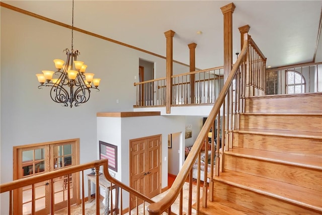 staircase with a notable chandelier, a towering ceiling, and ornamental molding