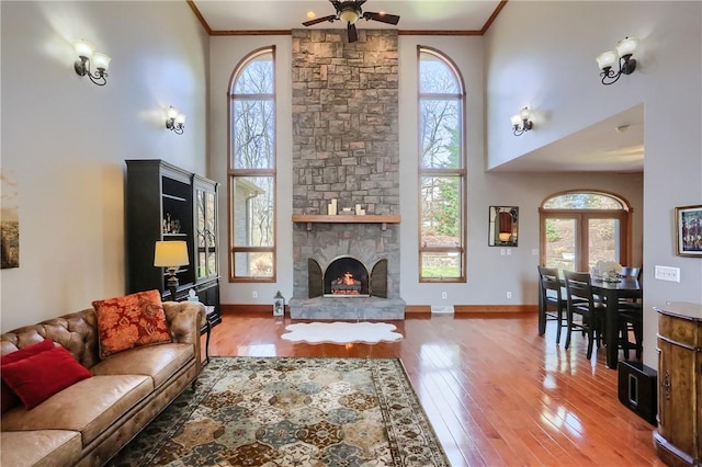 living room featuring wood-type flooring, a high ceiling, ceiling fan, and crown molding