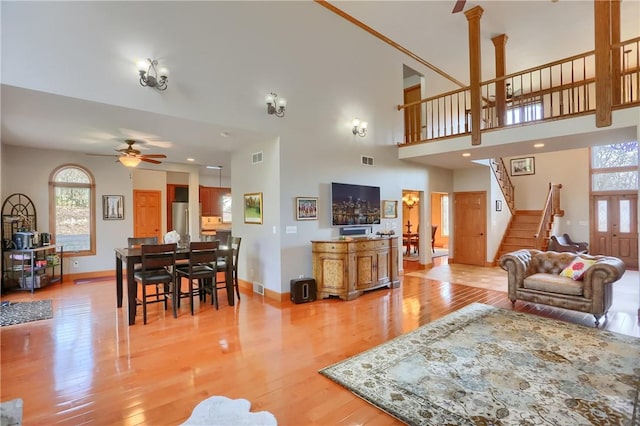 living area with light wood-style floors, visible vents, stairs, and a ceiling fan