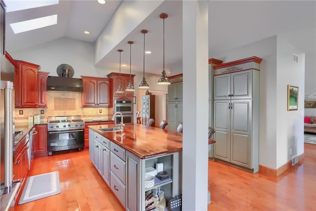 kitchen with visible vents, light wood finished floors, an island with sink, a sink, and appliances with stainless steel finishes