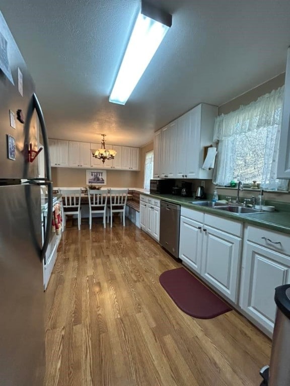 kitchen with a chandelier, white cabinets, stainless steel appliances, and a sink