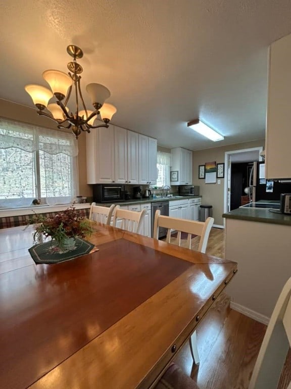 dining area with a notable chandelier, plenty of natural light, baseboards, and wood finished floors