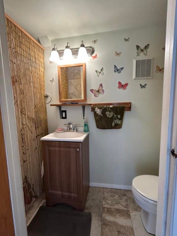 bathroom with visible vents, toilet, vanity, and baseboards