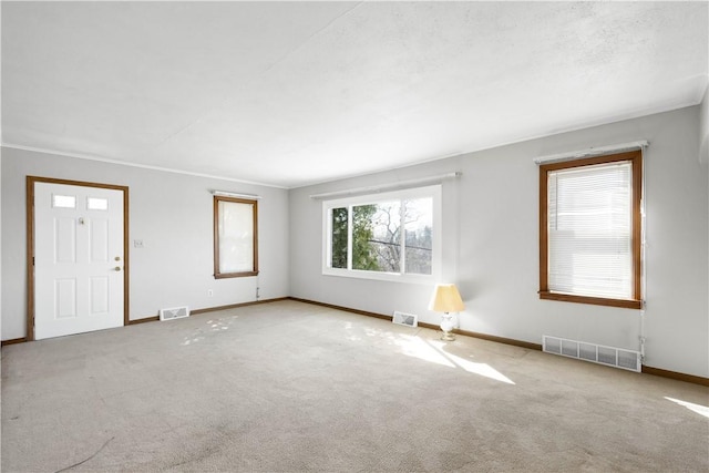 unfurnished living room with carpet, visible vents, and baseboards