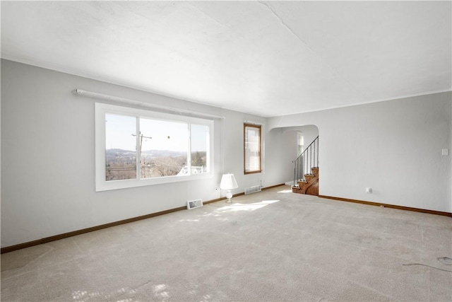 unfurnished living room with visible vents, arched walkways, carpet floors, baseboards, and stairs