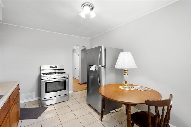 kitchen featuring visible vents, stainless steel appliances, arched walkways, light tile patterned flooring, and light countertops