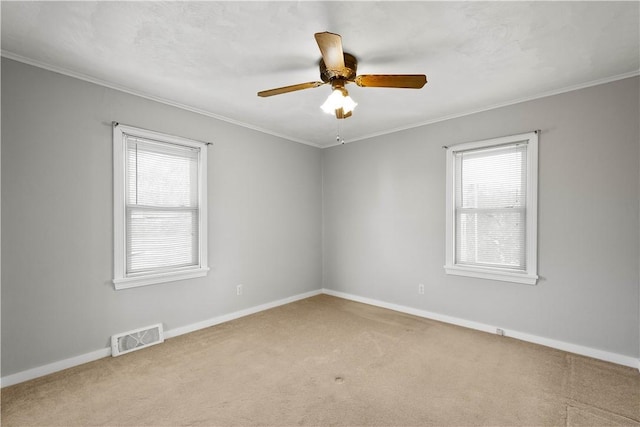 carpeted empty room with visible vents, a healthy amount of sunlight, and ornamental molding