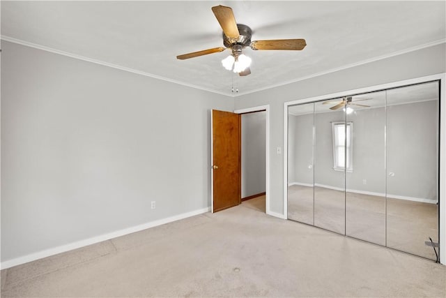 unfurnished bedroom with ornamental molding, a closet, carpet flooring, baseboards, and ceiling fan