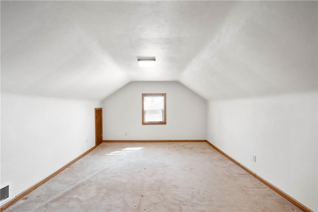 additional living space featuring vaulted ceiling, visible vents, baseboards, and light carpet