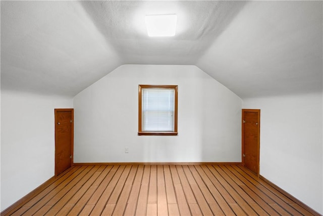 additional living space with baseboards, lofted ceiling, and wood finished floors