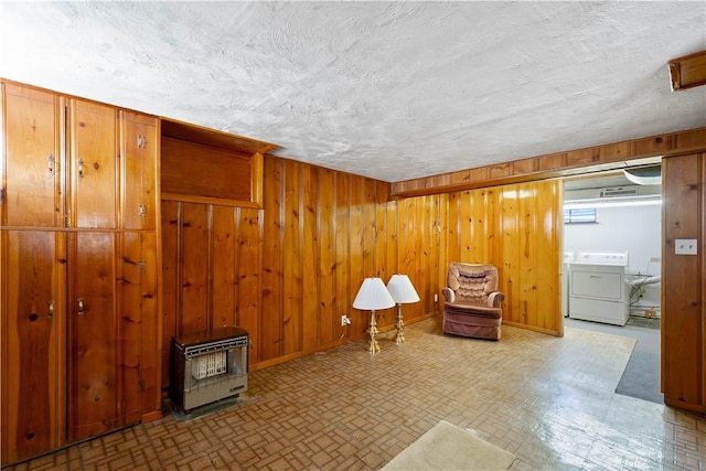 living area featuring washer / clothes dryer, wooden walls, a wood stove, and a textured ceiling