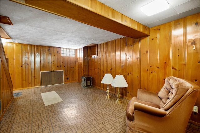 living area featuring wooden walls, baseboards, and visible vents