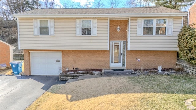 split foyer home with a garage, brick siding, and driveway