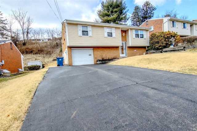 bi-level home featuring brick siding, driveway, a front lawn, and a garage
