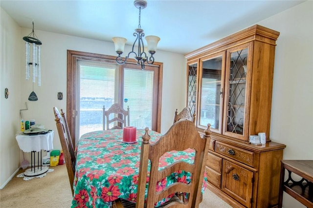 dining space with baseboards, light carpet, and a chandelier