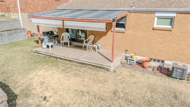 back of property with a patio area, brick siding, roof with shingles, and a lawn