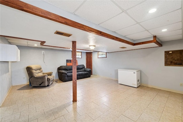 finished below grade area featuring visible vents, recessed lighting, refrigerator, and a drop ceiling