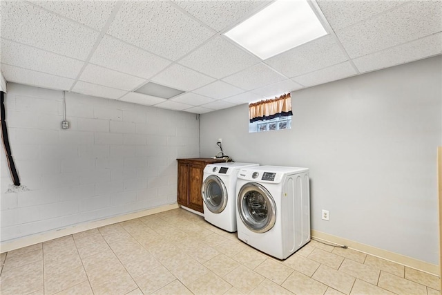 laundry room with baseboards, cabinet space, concrete block wall, and washing machine and clothes dryer