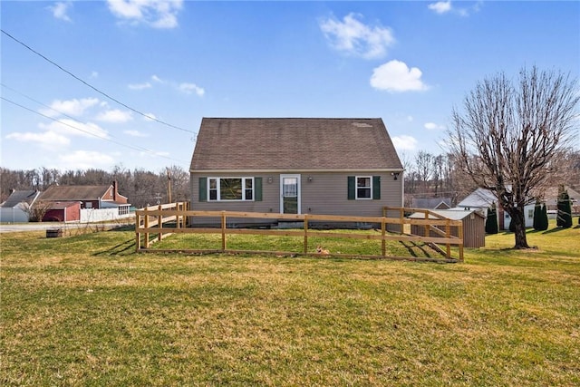 rear view of property with an outbuilding, a lawn, and fence